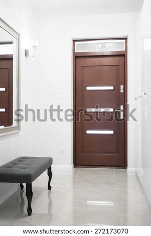 Photo of wooden entrance door in big white hallway