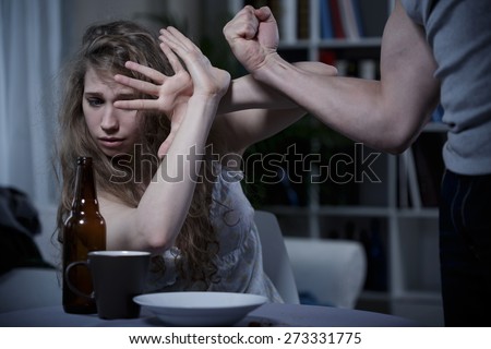 Terrified young woman defending herself from violent husband