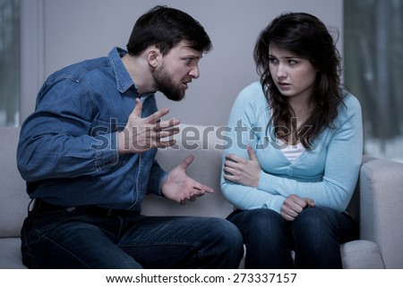 Young aggressive man screaming on scared woman