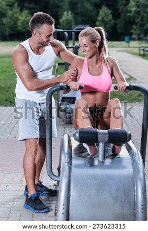 Women excercise on rowing machine with sport instructor