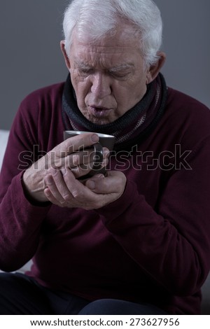 Senior man with cold drinking hot tea
