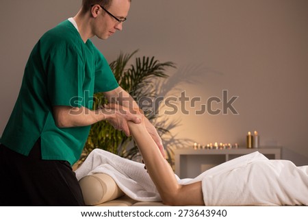 Masseur massaging lower limb of young woman