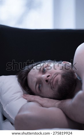 Close-up of young wake up man trying to fall asleep