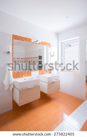 Bright bathroom with orange tiles and two basins