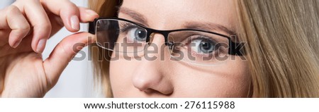 Close-up of young woman\'s blue eyes behind glasses