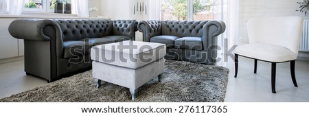Panorama of black leather sofa in bright living room