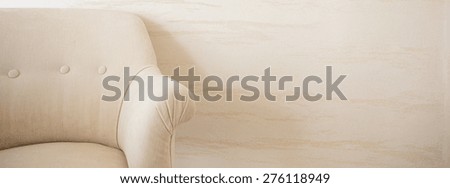 Beige armchair on a bright wall background, panorama
