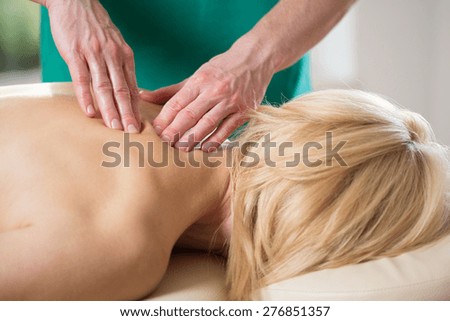 Physical therapist\'s hands massaging tense vertebral muscles