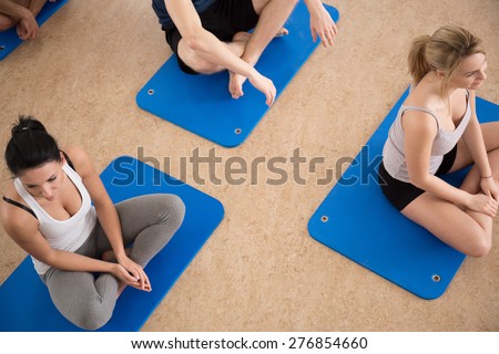 Gym people sitting on exercise floor mat