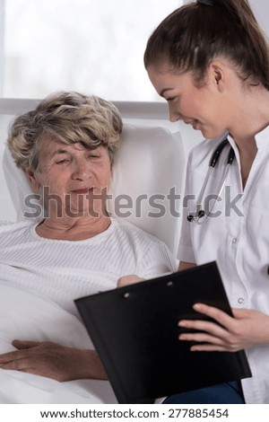Geriatric patient lying in bed and young nurse