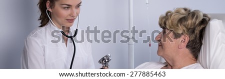 Panorama of young doctor examining elder woman