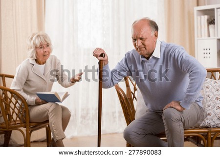 Senior man with knee arthritis and caring wife