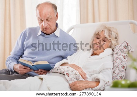 Image of husband reading ill wife book