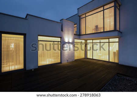 Big modern house with wooden porch at night