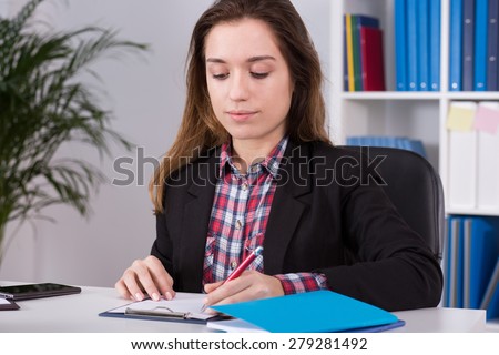 Young busy woman filling documents in office