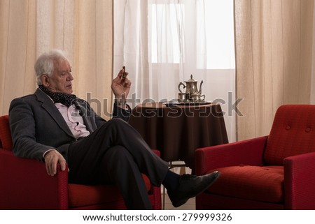 Older rich man sitting alone in his stylish lounge
