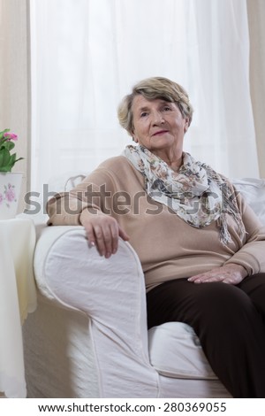 Calm elderly lady sitting alone in her room