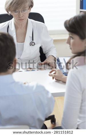 Infertile couple and female disgruntled doctor talking about in vitro