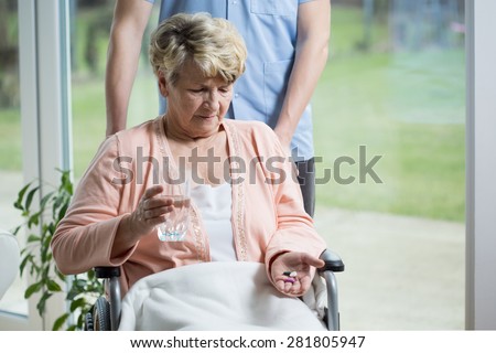 Old woman on a wheelchair taking pills