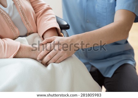 Nurse holding hands of a woman on a wheelchair