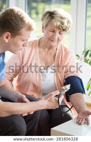 Young male nurse taking blood pressure
