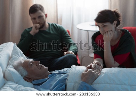 Young worried daughter sitting with her terminally ill father