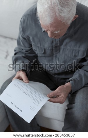 Old man sitting on a couch and worrying about money