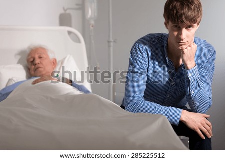 Young man sitting by his sick grandfather