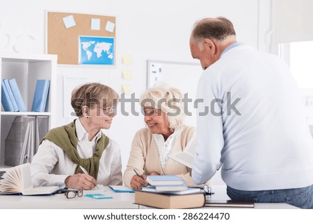 Image of smiling elder people studying in library