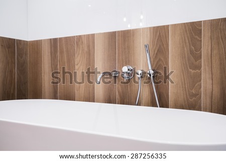 Close-up of white bathtub with wooden panel