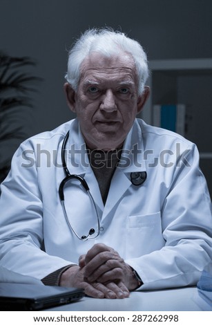 Portrait of older serious sad doctor in his office