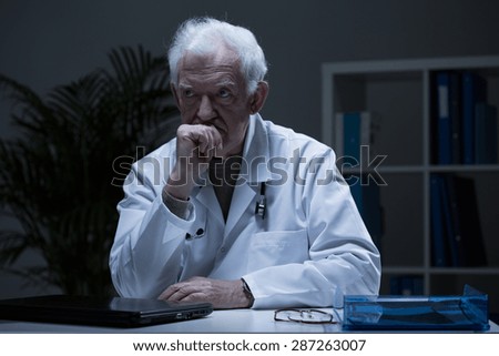 Elderly physician sitting alone in his office after work