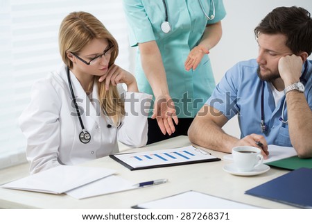 Three doctors in doctors room during medical consultation