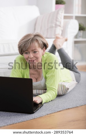 Elderly happy woman surfing the internet on laptop