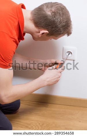 Man is repairing electrical socket in the house