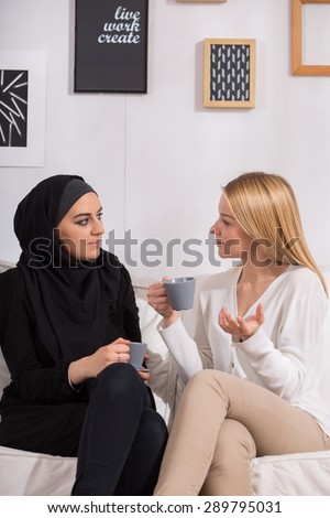 Multicultural female friends drinking coffee and discussing