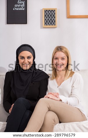 Smiling muslim and christian women being friends