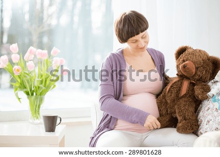 Future mom holding brown teddy bear