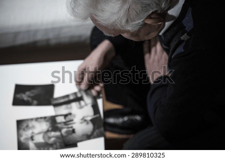 Sad widower watching pictures with his dead wife