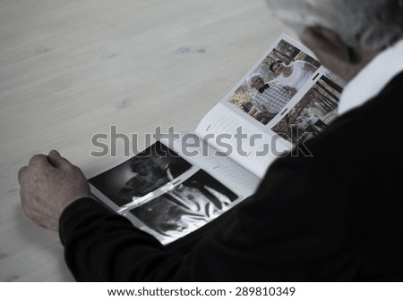 Lonely elder man looking into family photo album