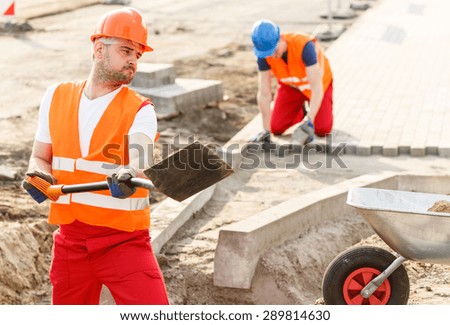 Young strong construction worker digging the ground