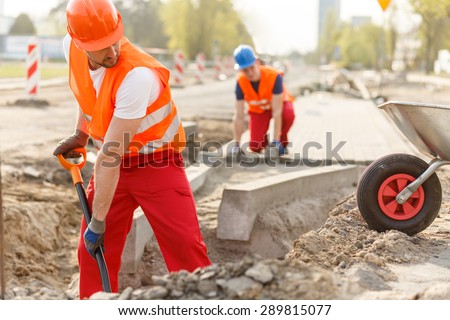 Two hard working builders in uniforms putting pavement
