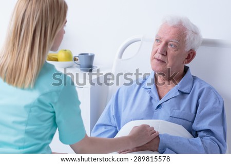 Carer visiting older sick man in hospital