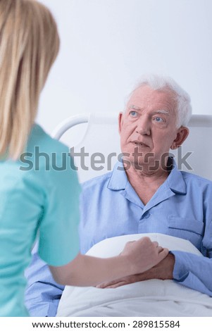 Worried sick older man and his helpful young caregiver