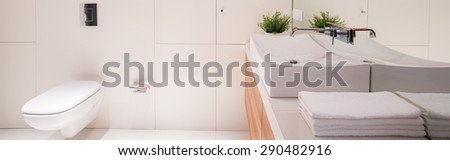 Panorama of white elegant restroom with basin and folded towels