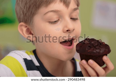 Hungry greedy child eating delicious chocolate cupcake