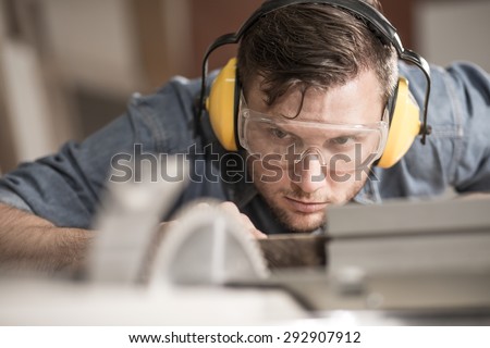 Carpenter while using electric tools wearing protective headphones