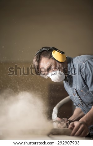 Carpenter wearing protective headphones while using electric saw