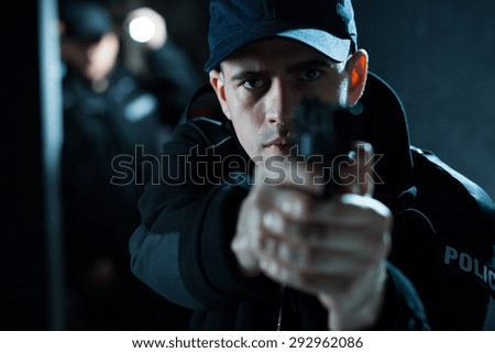 Close up of an armed policeman pointing pistol
