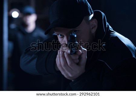 Image of a focused policeman aiming gun during intervention